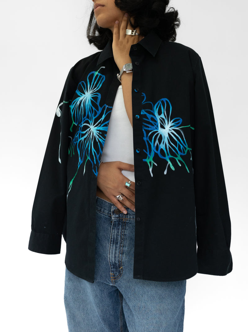 Person wearing a black shirt with blue floral designs on a white background
